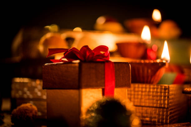 Diwali diya or lighting in the night with gifts, flowers over moody background. Selective focus